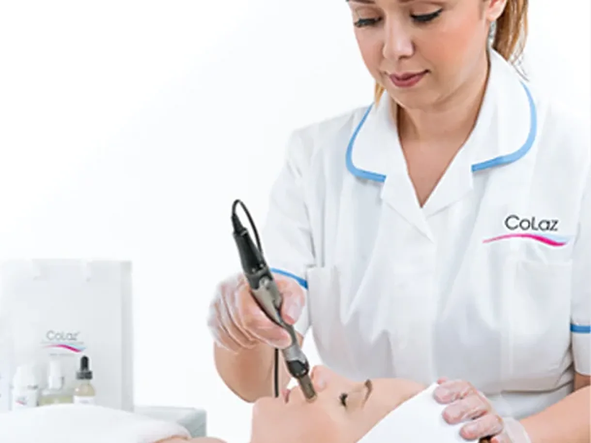 A CoLaz clinician in branded uniform using the HydraFacial handpiece on a client